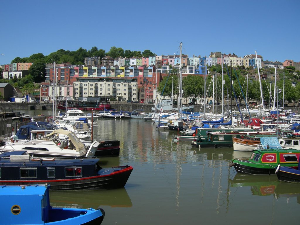 Bristol Marina colourful riverboat houses moored on the river with beautiful coloured terrace houses in the distance.